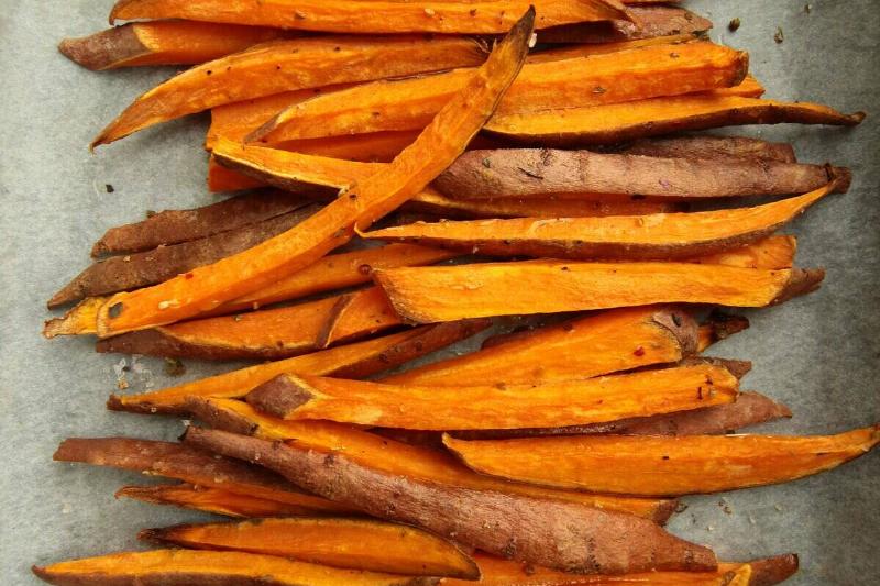 Uncooked sweet potato fries on parchment paper