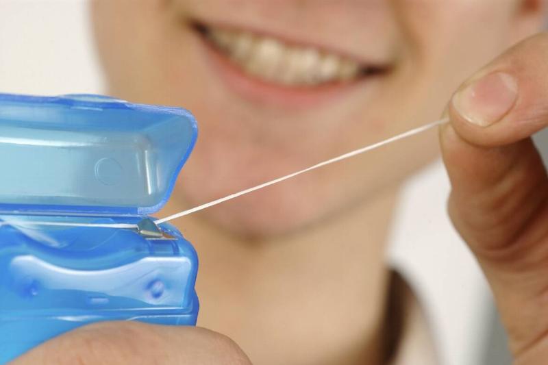 Close-up of a man holding dental floss in front of his face