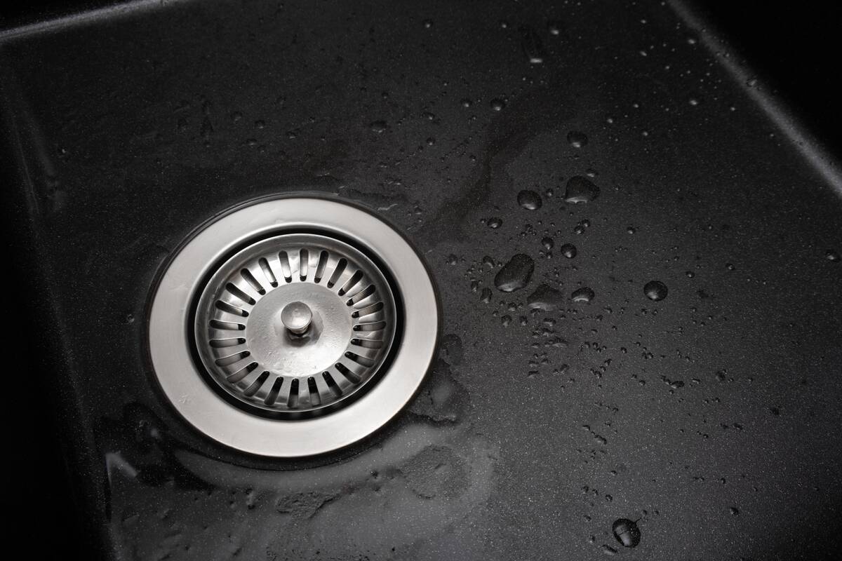 Metal drain plug in the drain of a black-colored sink