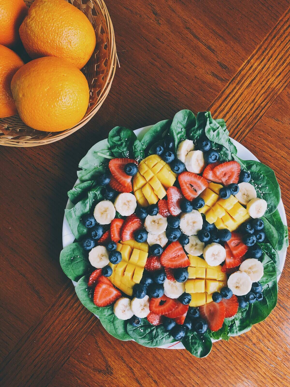 Overhead view of a fruit plate next to a basket of oranges