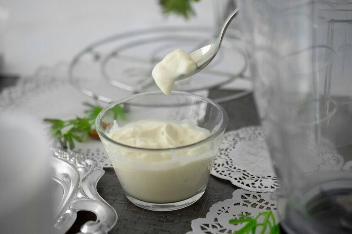 A metal spoon scooping Greek yogurt from a glass bowl
