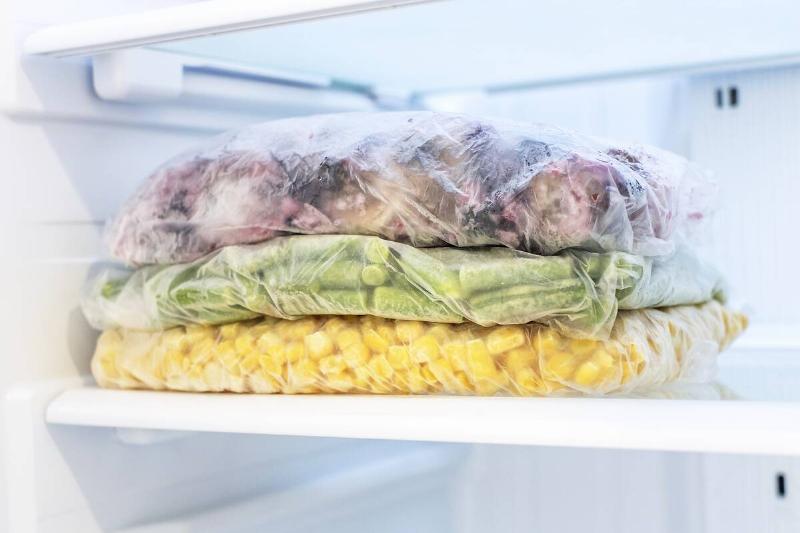 Three bags of vegetables in a freezer