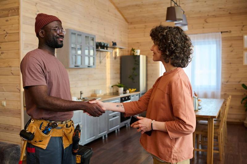 Contractor and woman shaking hands in the middle of a kitchen