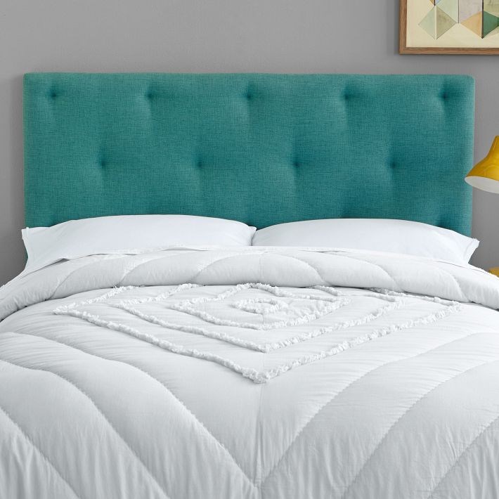 Teal tufted headboard meets a gold reading lamp