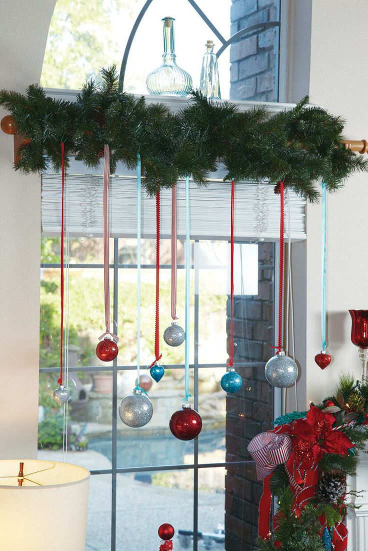 Colorful glittery ornaments hung with ribbon from garland above window
