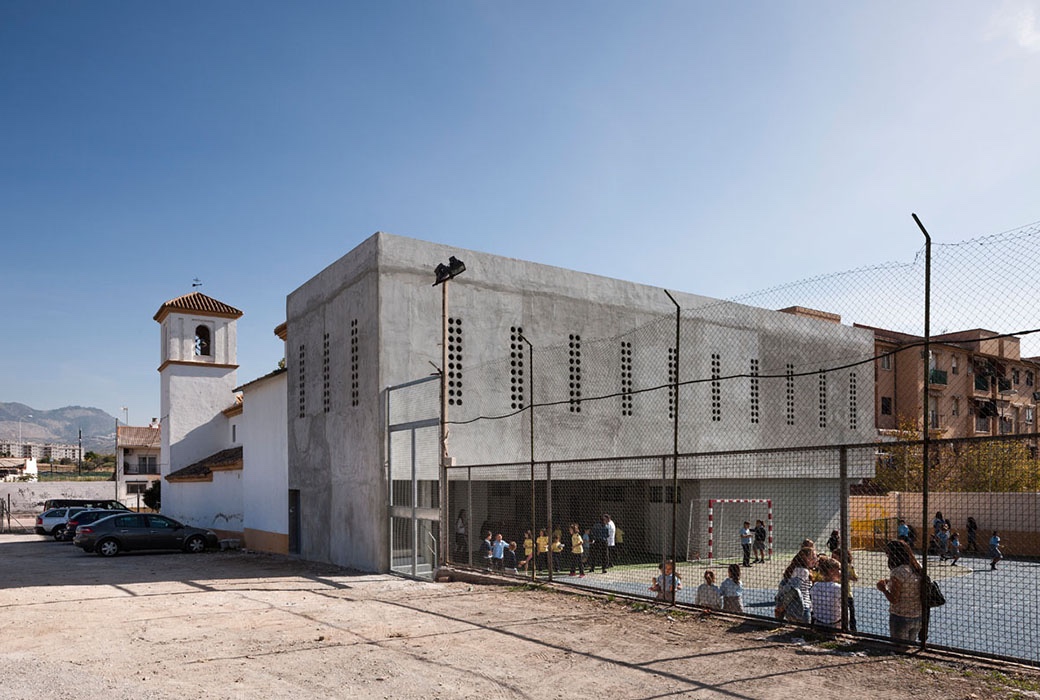 Tiny porthole windows punctuate the multipurpose hall at the Cerrillo de Maracena School in Granada.