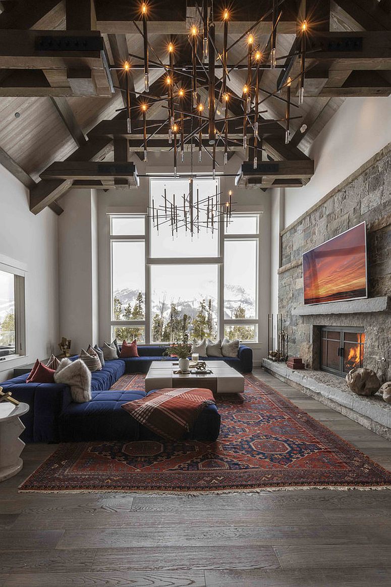 Vaulted ceiling, brilliant chandelier and wooden accent wall shape this spacious living room