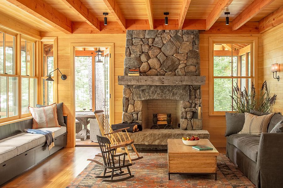 Wood-clad living room with comy benches and a stone fireplace