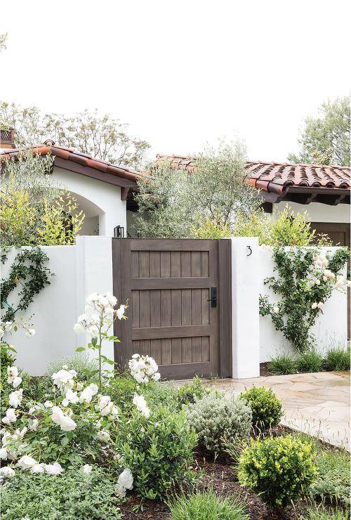Modern metal house numbers on a white brick fence beside a rustic wooden gate in a transitional outdoor entry home design.