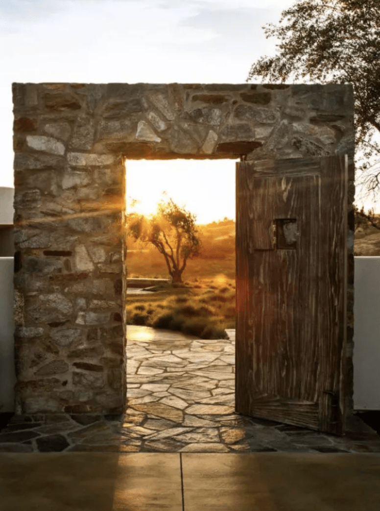 old stone wall with rustic wooden gate door leading into patio garden