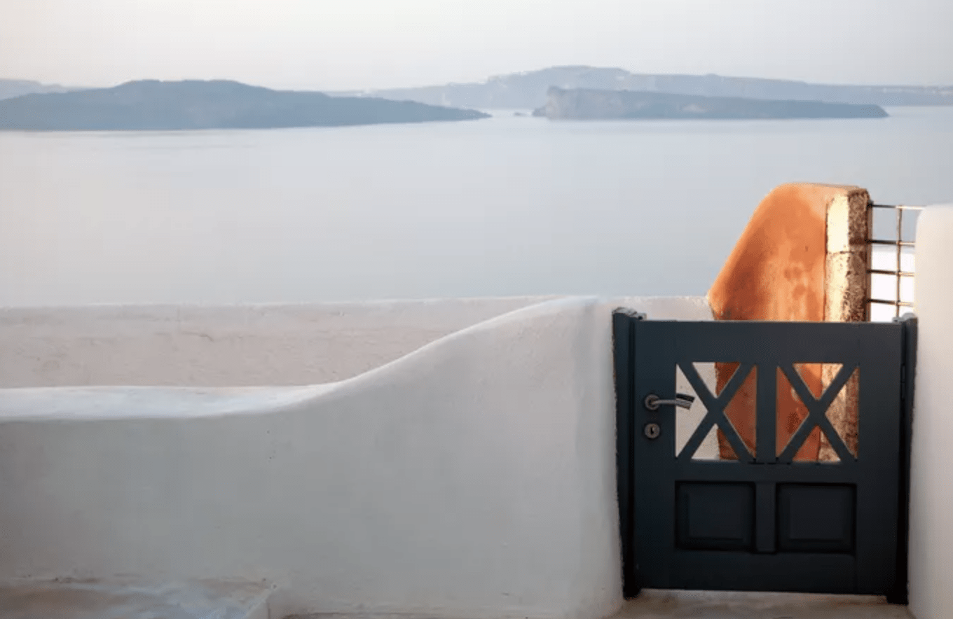 small wooden gate with stucco wall ocean in background