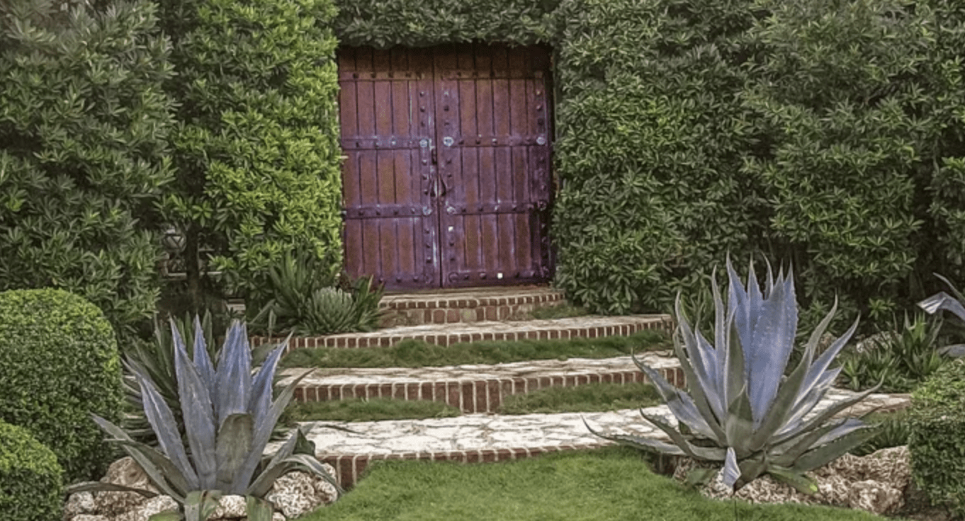 large wooded gate surrounded by hedges