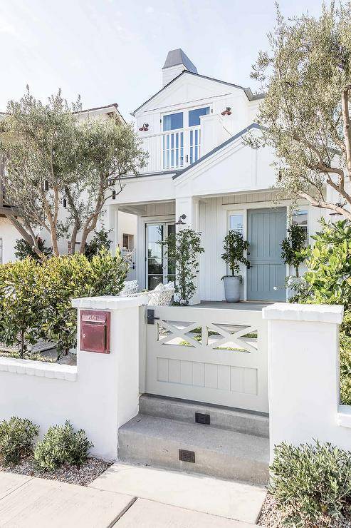 A cottage style home with a mini gray front gate boasts a vintage mail slot.