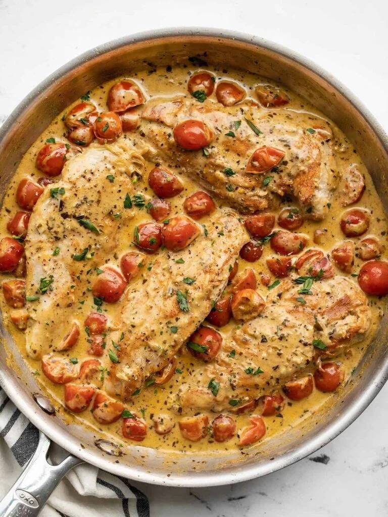 creamy pesto chicken dish with tomatoes in large saute pan